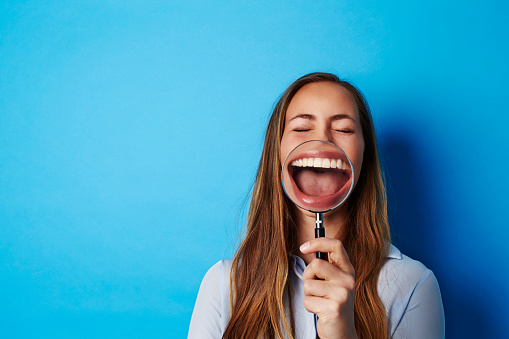 Beautiful woman laughing through magnifying glass