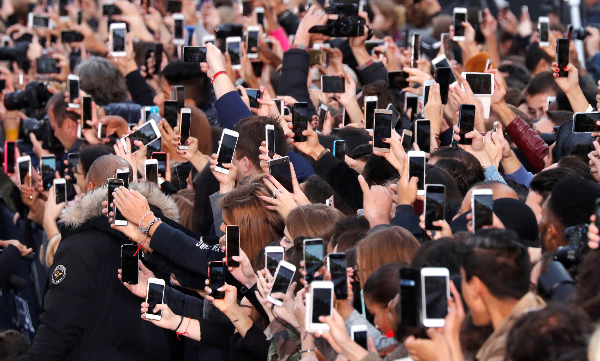 Image: People use their smartphone to take photos on the Champs Elysees avenue during a public event in Paris